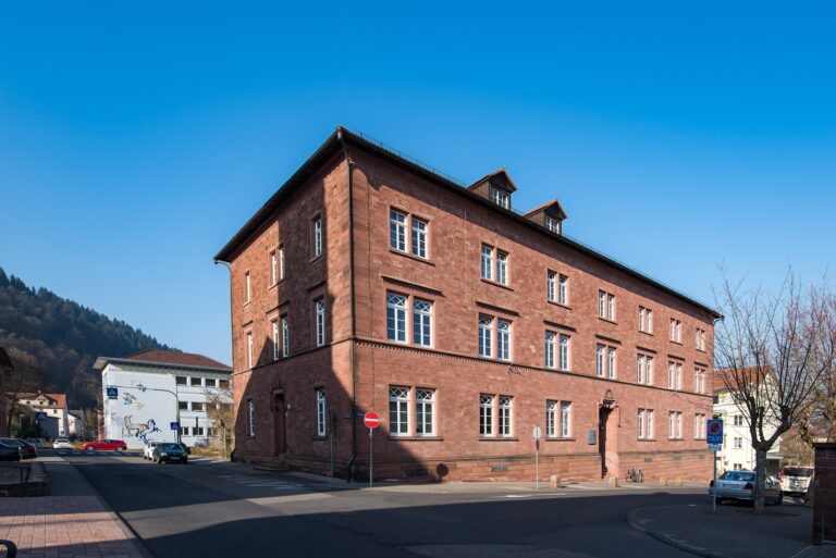 Dreistöckiges Amtsgerichtsgebäude aus rotem Sandstein an einer Straßenecke unter blauem Himmel